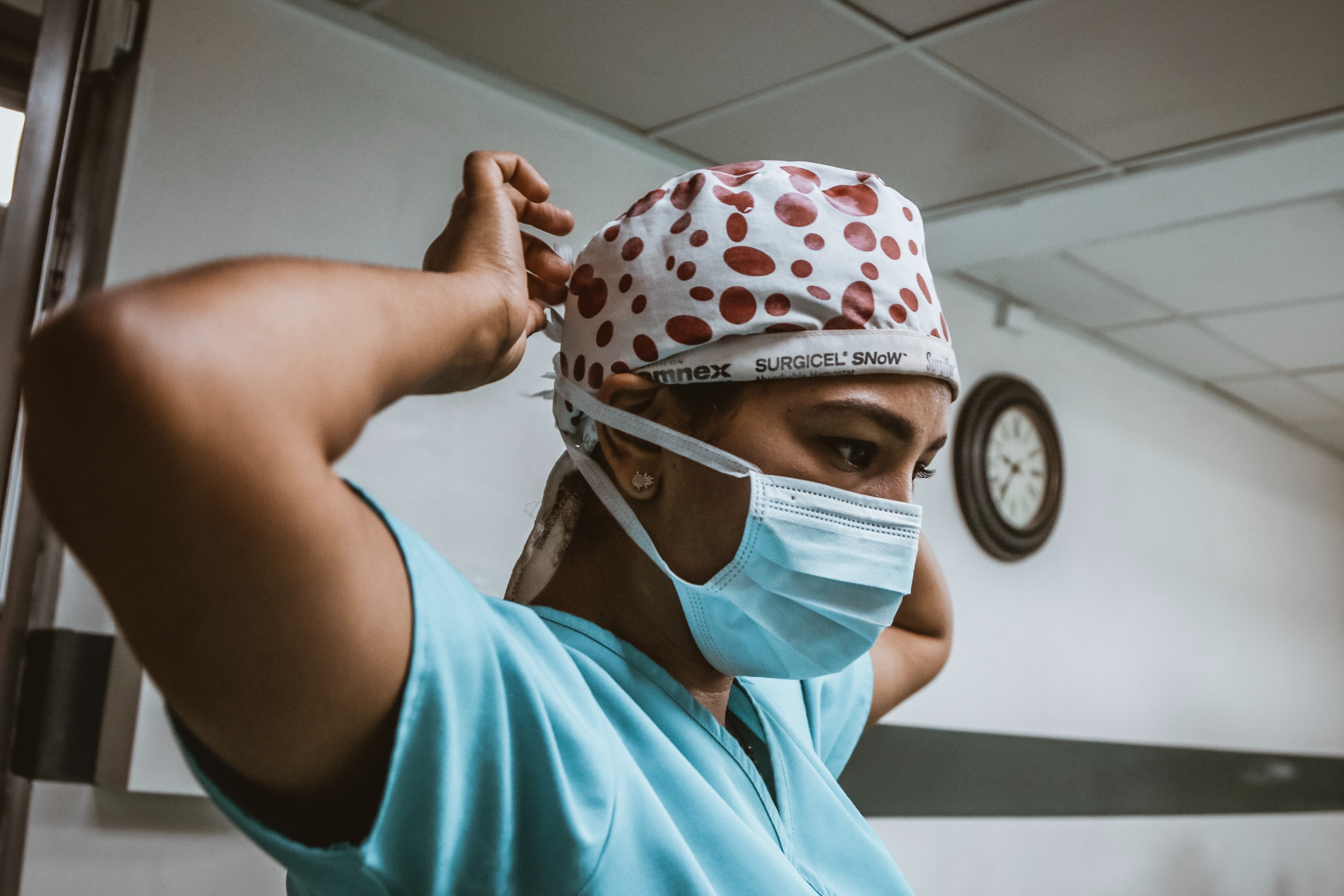 Bild på sjuksköterska som knyter huvudbonad. 